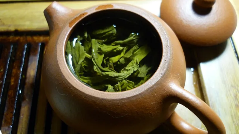 Green leaves and clear liquor inside a glass teapot