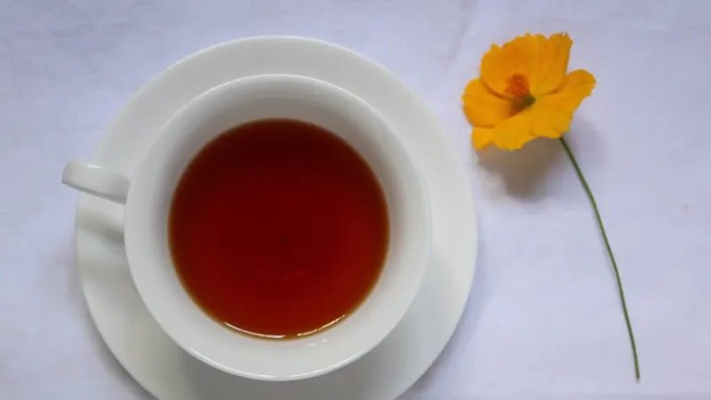 A cup of aromatic oolong tea beside a yellow flower